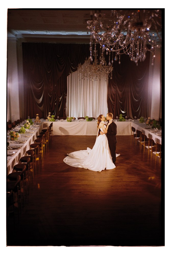 Bride and groom first dance in ballroom during luxury wedding reception