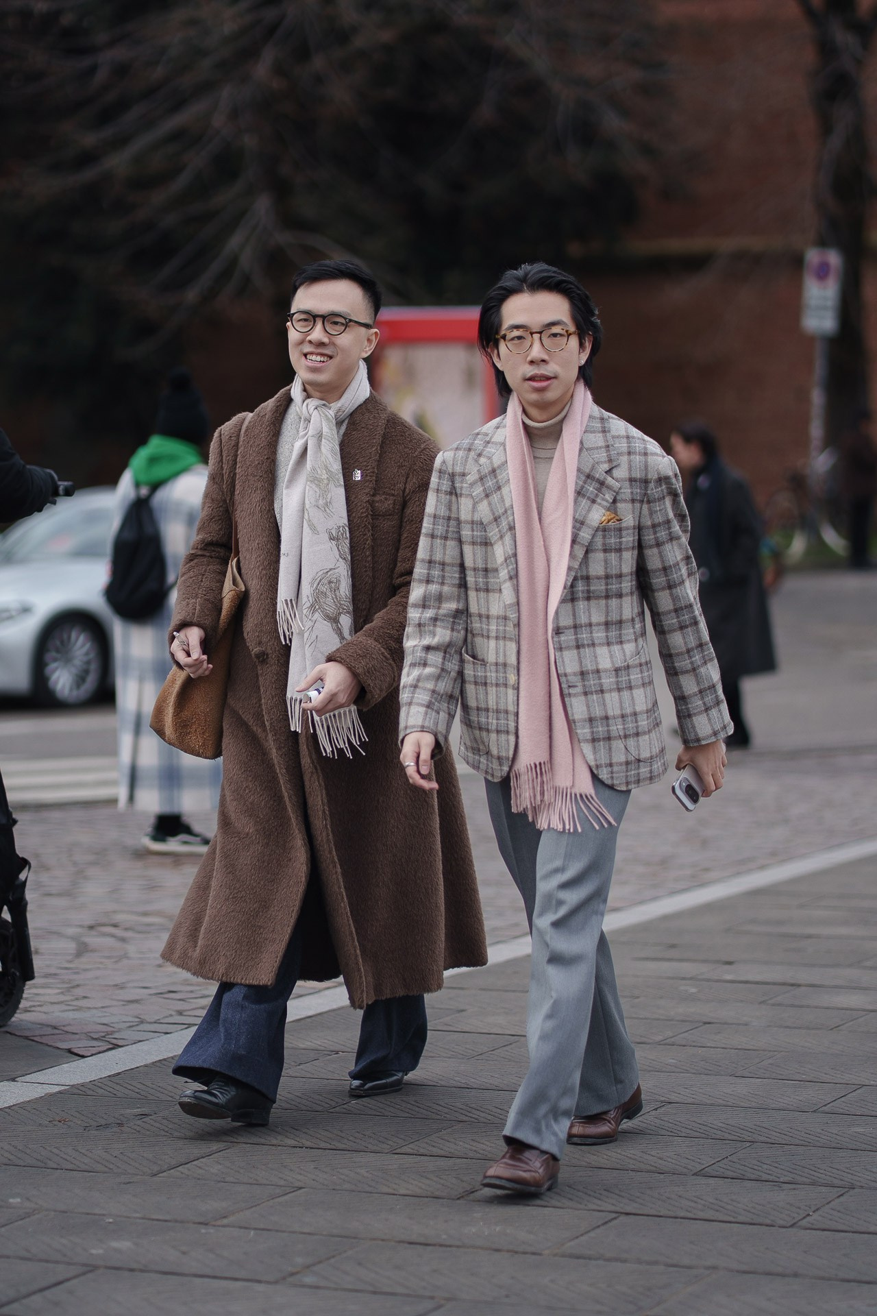 Two stylish men in coats and scarves walking at Pitti Uomo 109 Florence