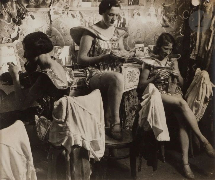 Фотография Брассая «Английские девушки в гримёрке Фоли-Бержер» (1932): несколько полураздетых женщин в зеркальной комнате готовятся к выступлению, окружённые косметикой и костюмами.