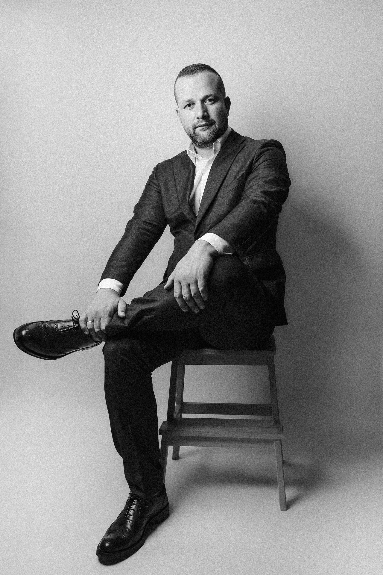 crno bela fotorgafija muškarca u odelu koji sedi prilikom portretnog fotografisanja