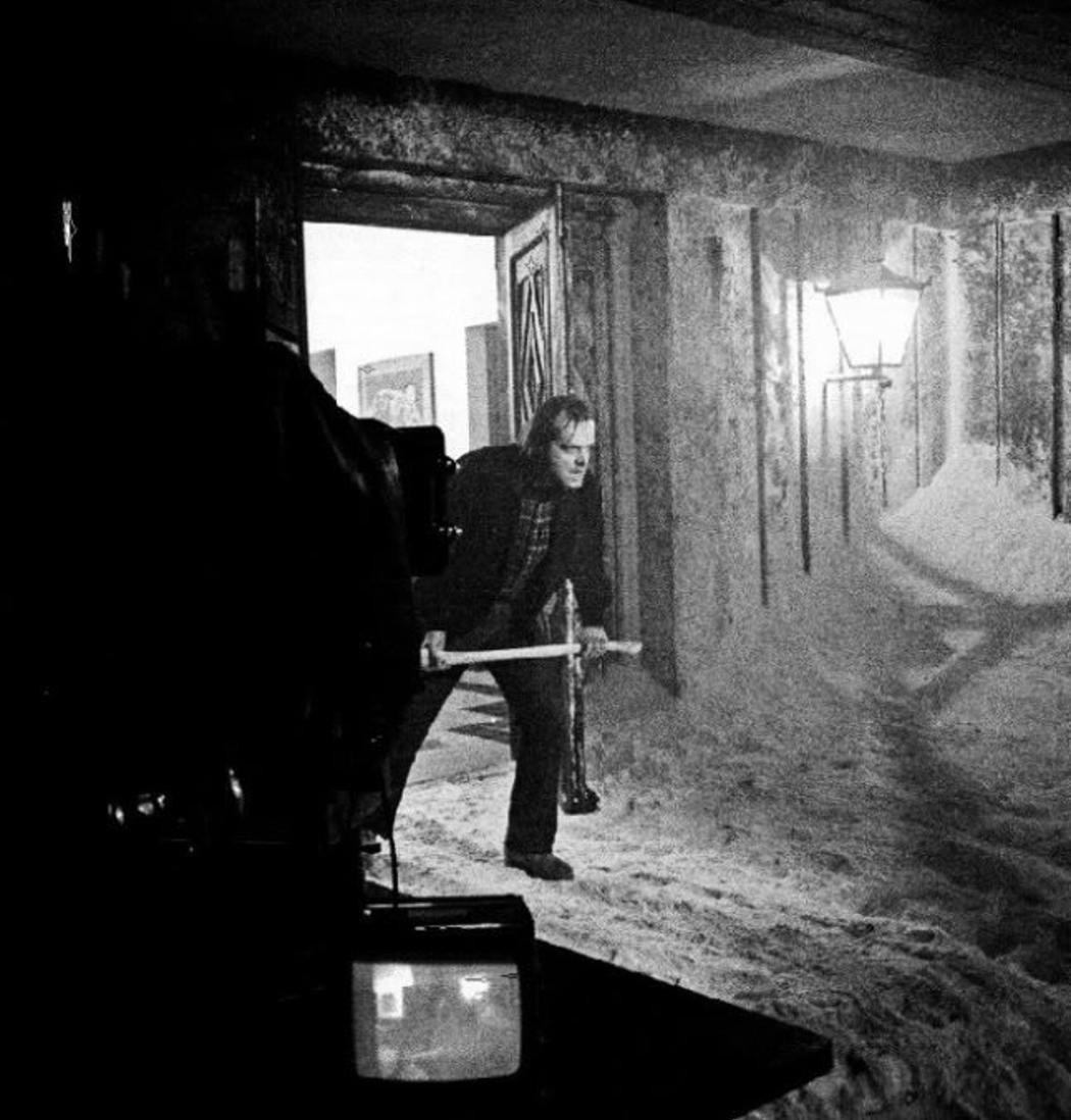 Кадр из хоррора «Сияние» 1980: Джек Николсон с безумной улыбкой выглядывает сквозь пробитую топором дверь — «Here’s Johnny!», отель Оверлук