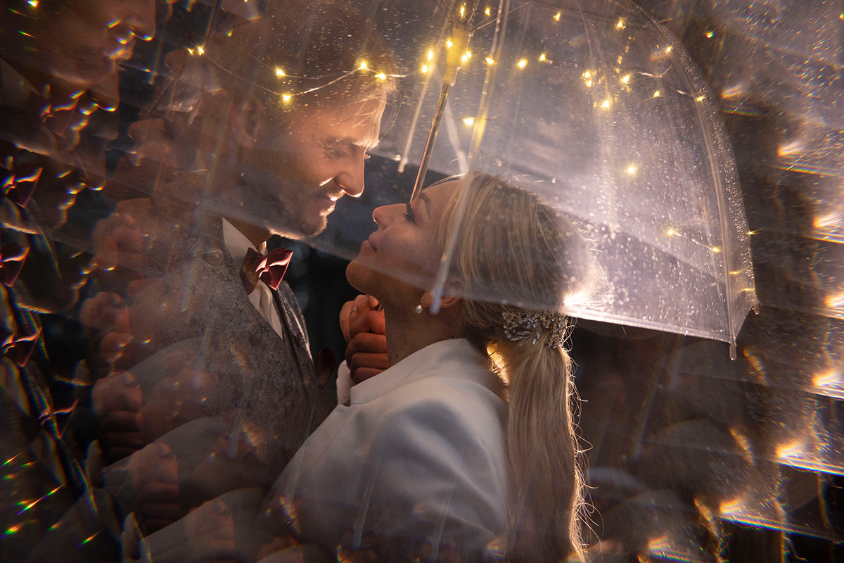 Brautpaar im Dunkeln unter dem durchsichtigen Schirm mit Lichtern,  kreatives bild