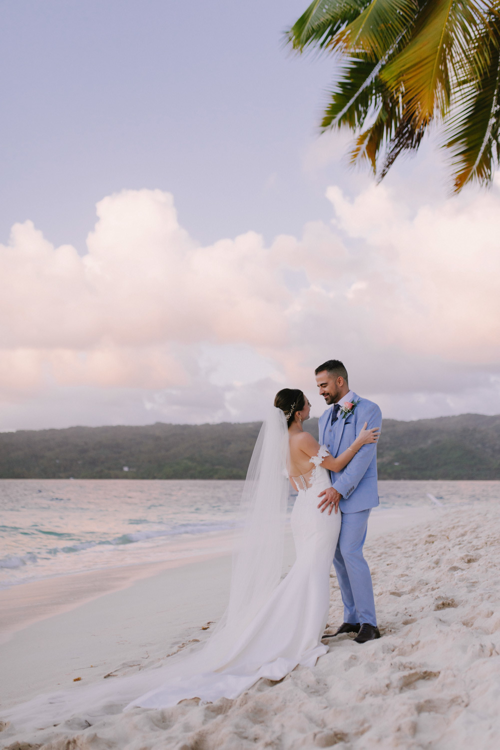 Bride and groom on the background of sea sand and rising rays of light.