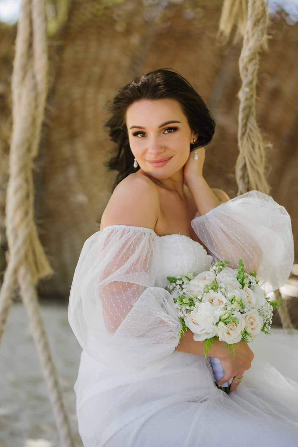 Bride with a bouquet of flowers on a brown background with hemp ropes.