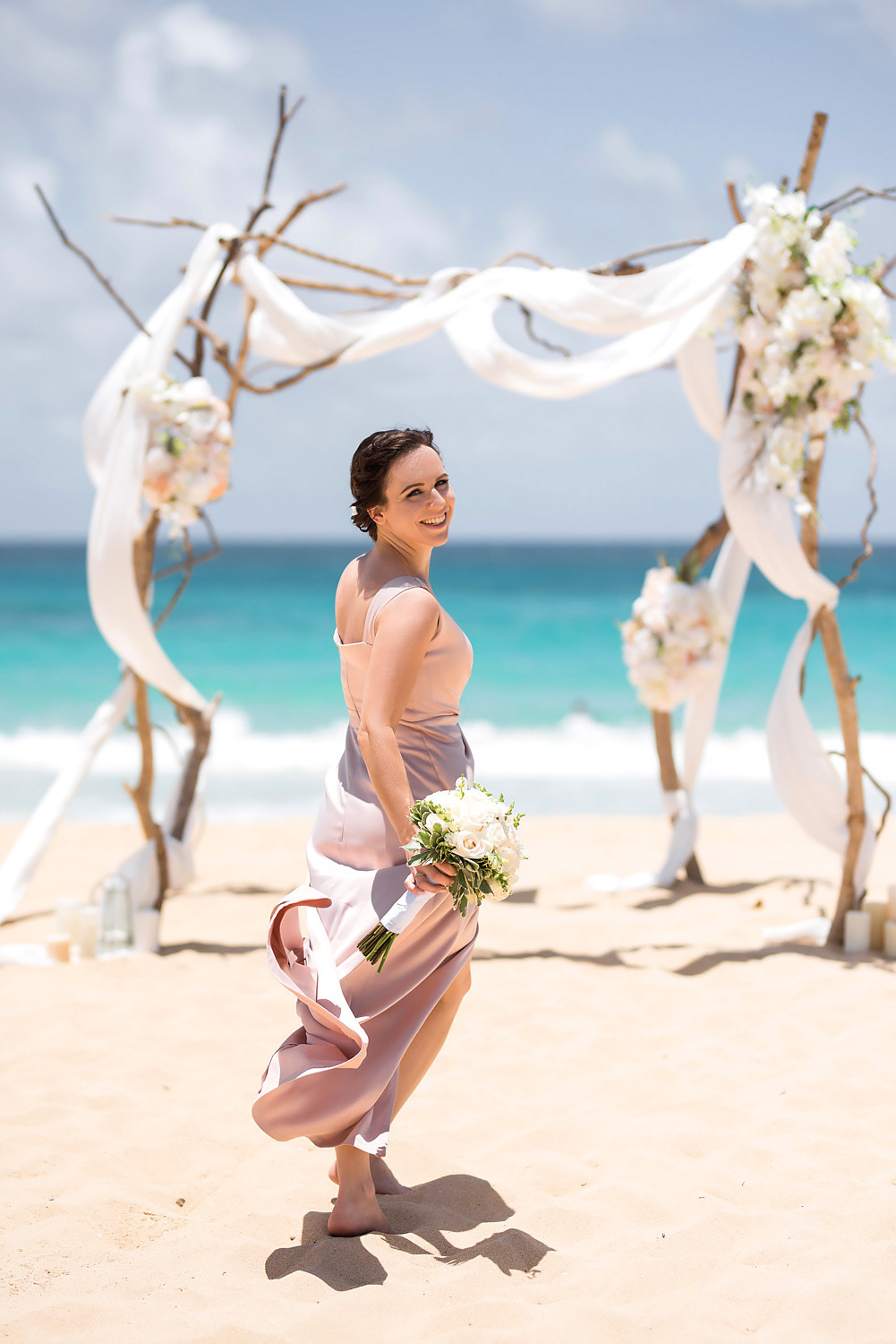 Невеста с букетом цветов на фоне алтаря и пенящихся волн моря.