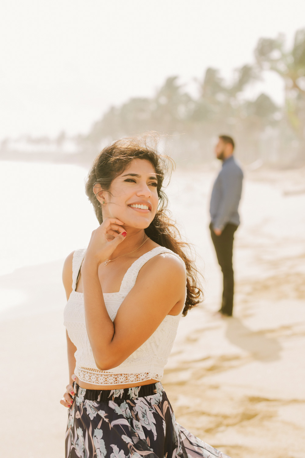 Невеста улыбается на фоне жениха, смотрящего в море.