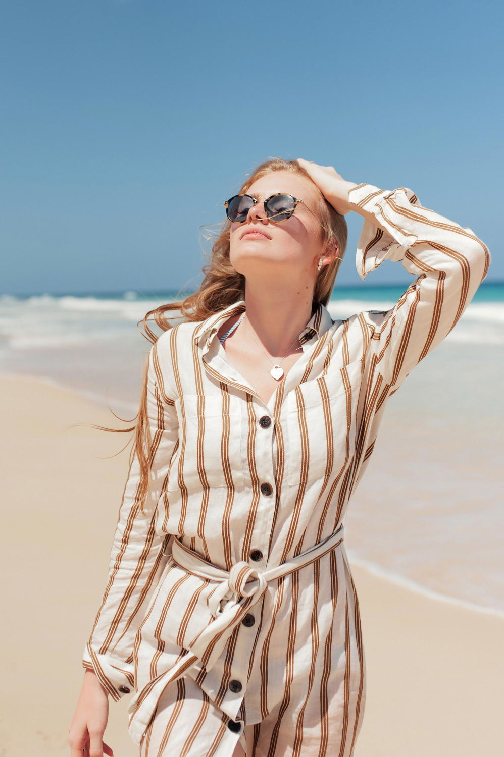 Head thrown back, a girl in dark glasses by the sea.