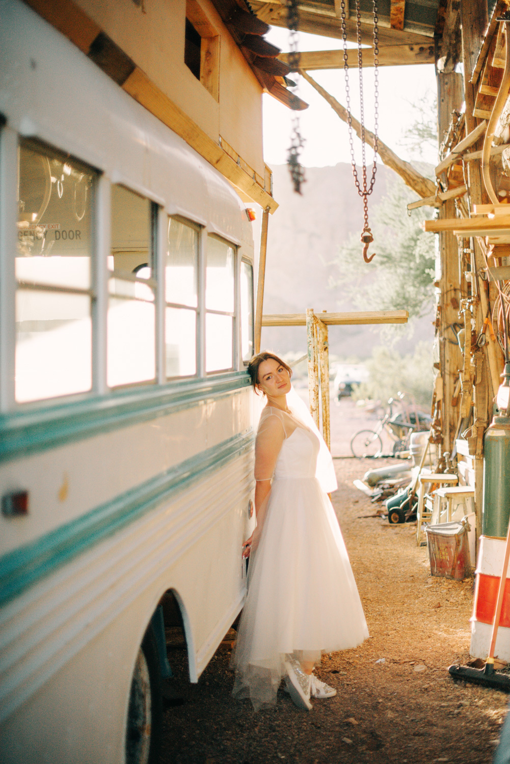 Невеста стоит облокотившись о старинный автобус в здании гаража.