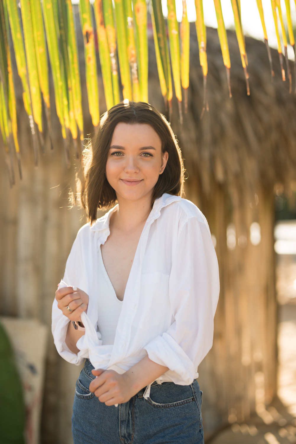 The bride in a white shirt and dark shorts under a palm tree.
