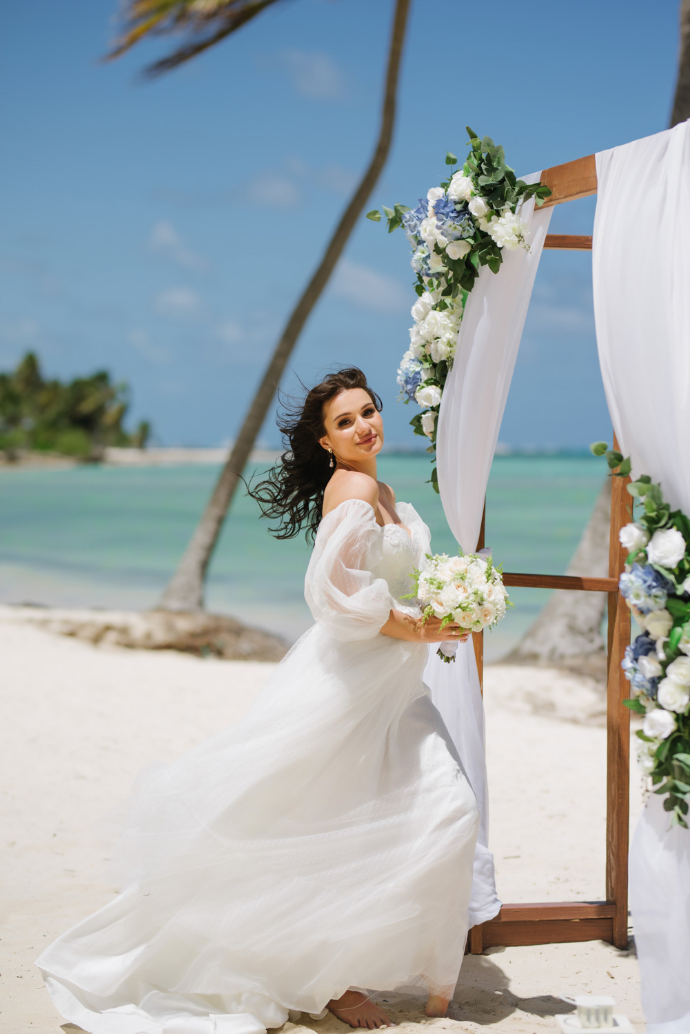 Bride with a bouquet of flowers at the altar on the background of the sea bay.