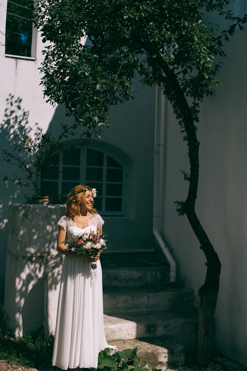 Bride in the shadow of the house on the background of the house window and trees.
