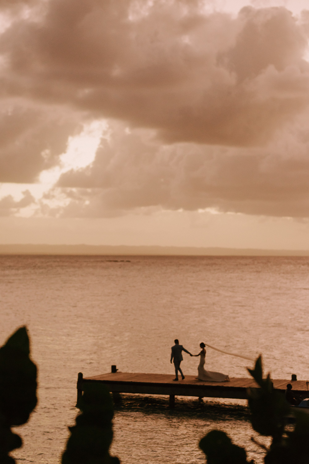 Silhouettes of the bride and groom on the pier in the evening light.