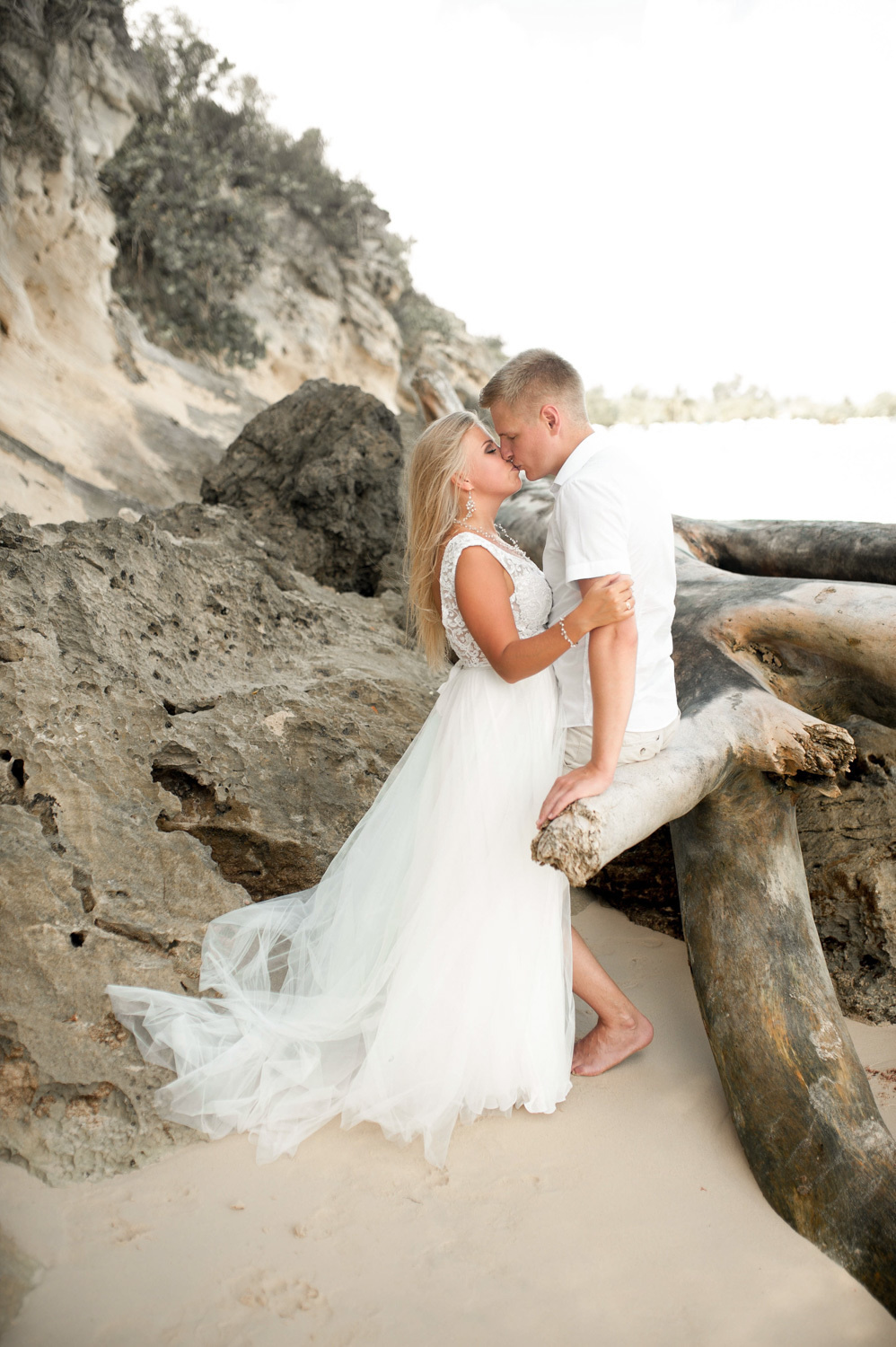 The bride and groom kiss on the background of rocks near the high seashore.