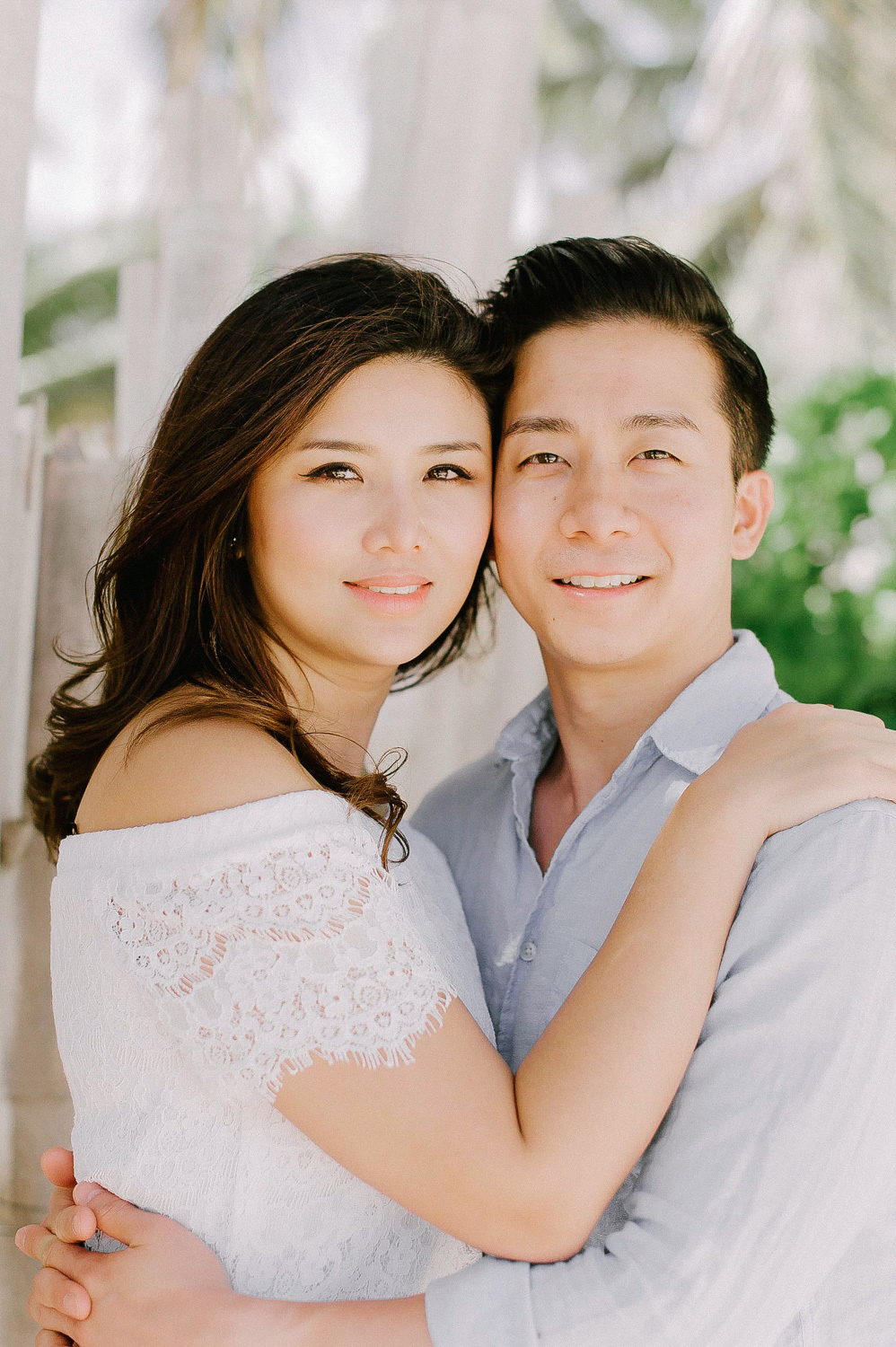 The groom puts his arm around the bride's waist, and she puts her hands on his shoulders.
