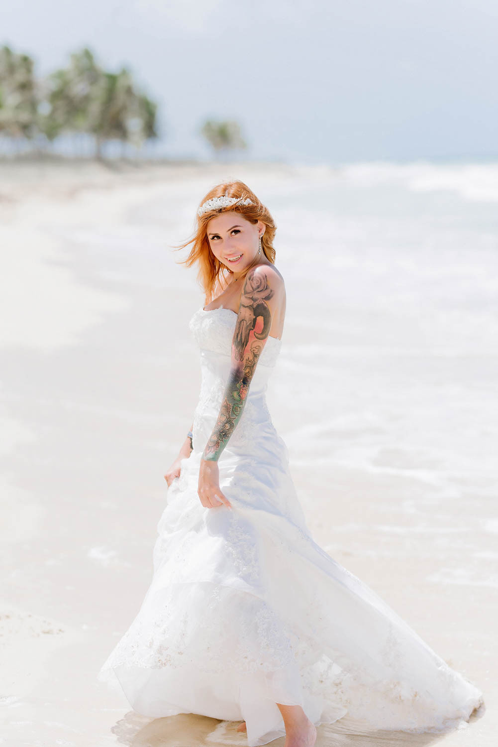 The bride turned sideways, showing off her hand in a colorful tattoo. There's a hair ornament in her hair.