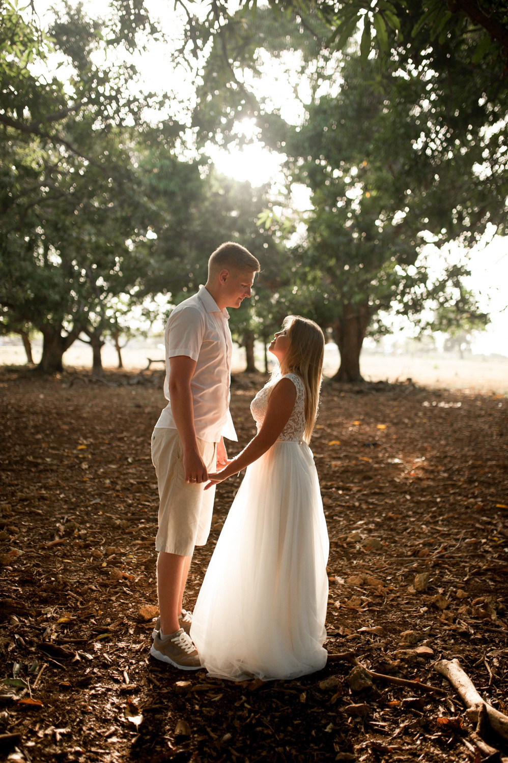 On the bride and groom fall the rays of the sun, breaking through the leaves of trees.
