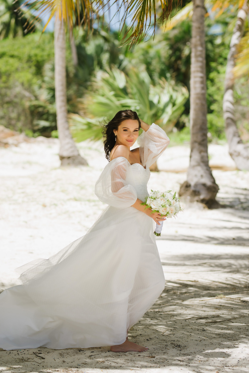 Bride with a bouquet of flowers on the background of the beach with palm trees.