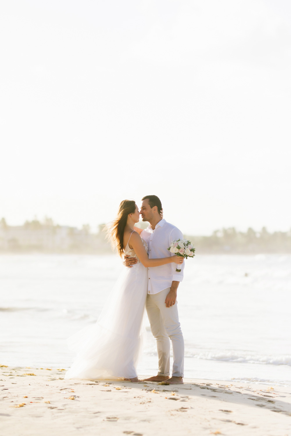 newlyweds embrace and gaze into each other's eyes on a sandy Caribbean beach