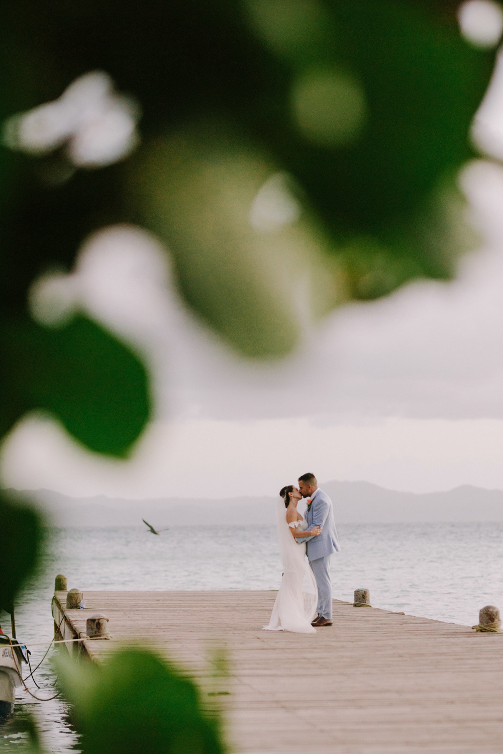 The bride and groom kiss on the sea pier.