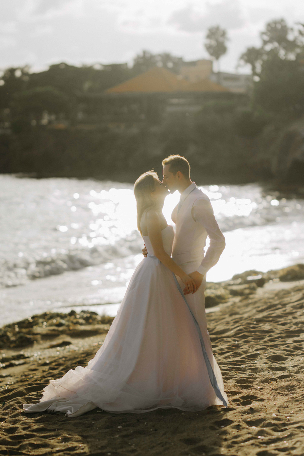Жених и невеста целуются на берегу морского залива.