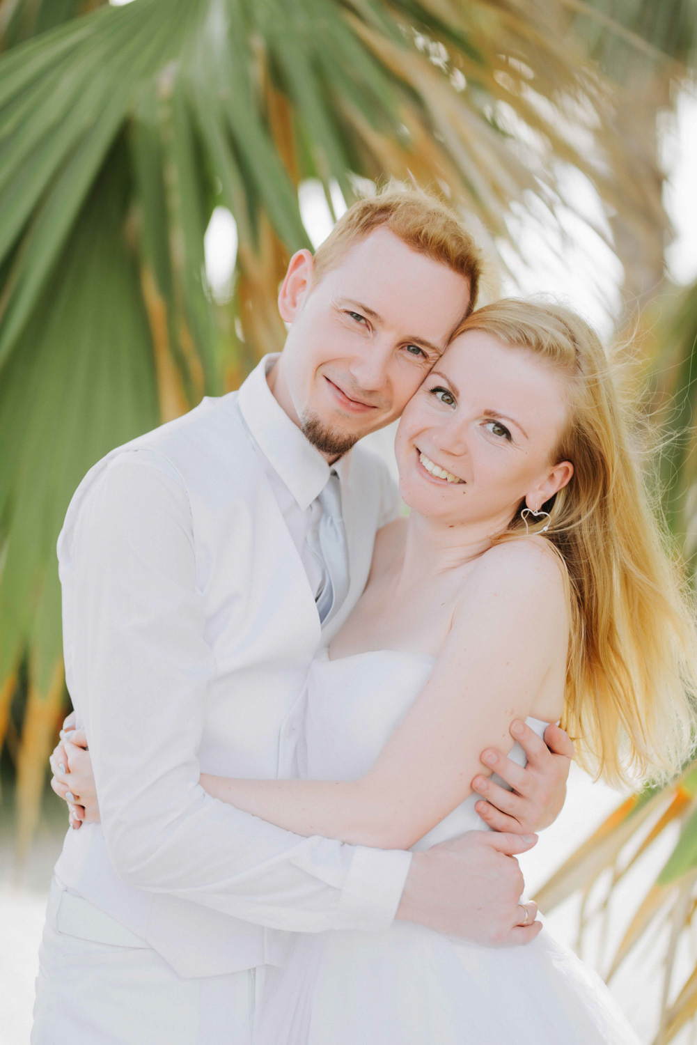 Жених с невестой обнимаются на фоне пальм.