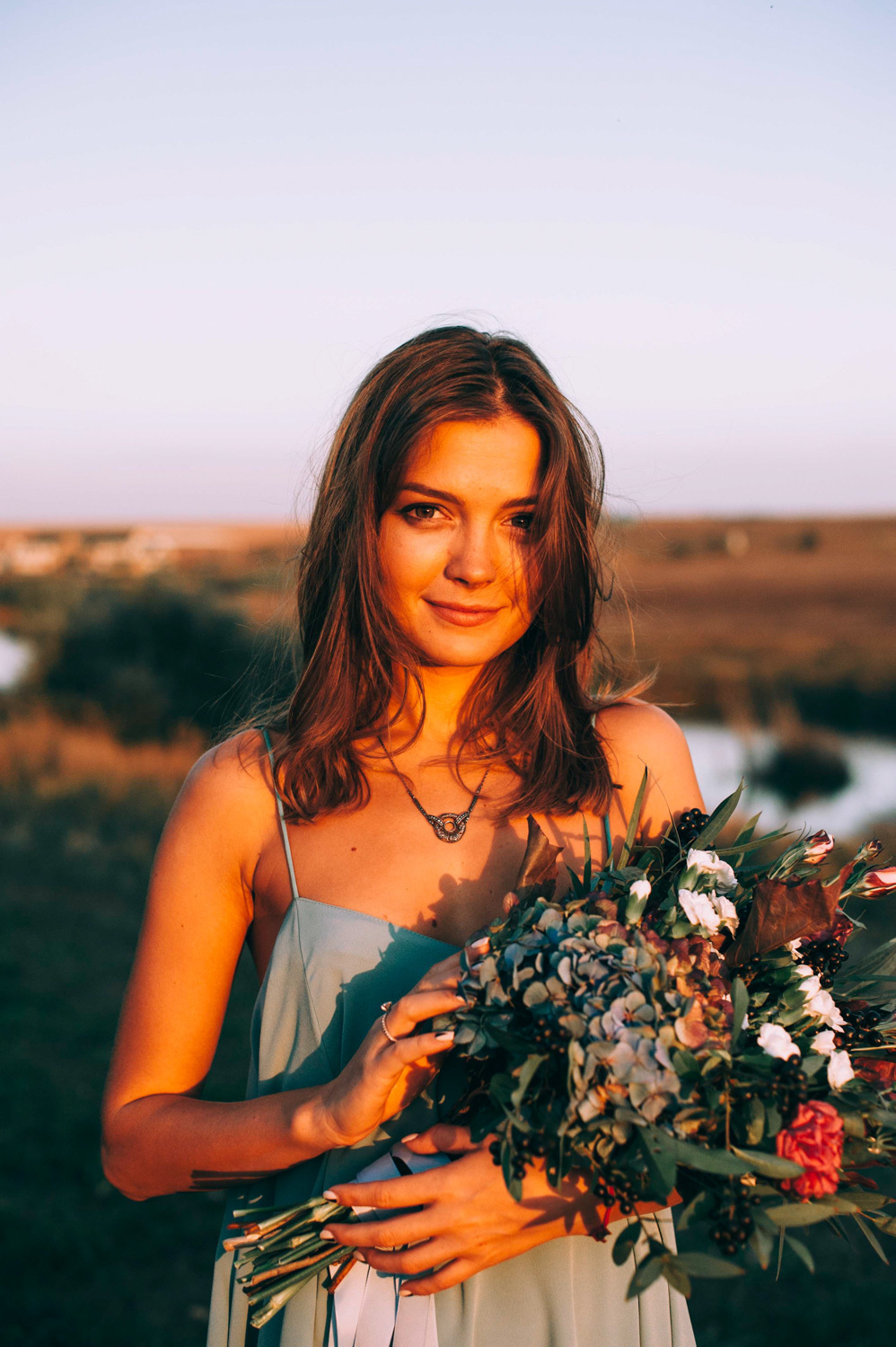Bride with a bouquet of flowers in the evening sun.
