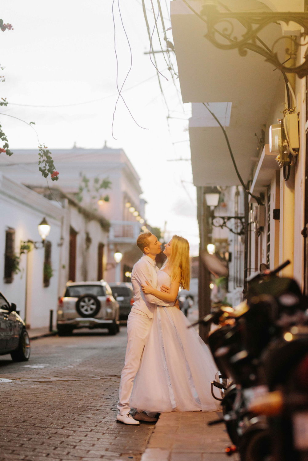 Жених и невеста целуются на фоне городской вечерней улицы.