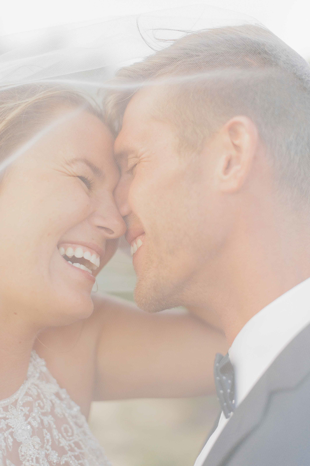 Smiling faces of newlyweds through a haze of veils.
