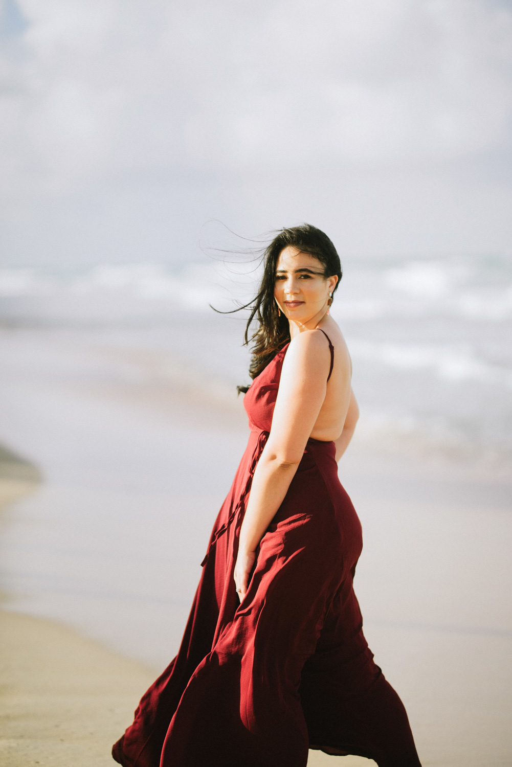 Невеста в длинном бардовом платье на фоне моря.