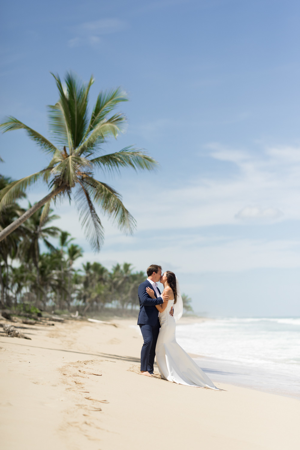 On the beach with palm trees, the footprints of the bride and groom kissing on the background of the sea.