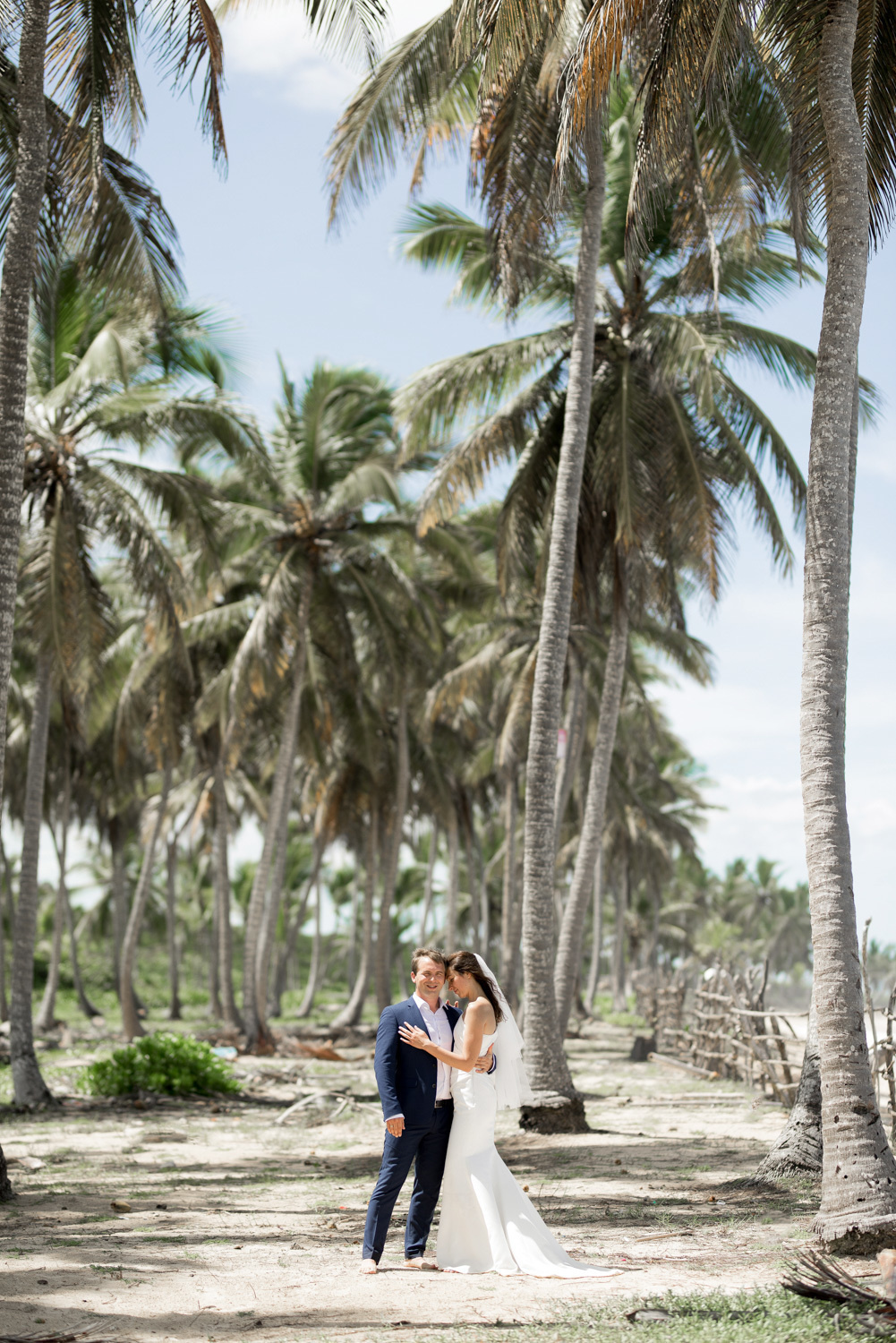 The bride and groom at the tall palm trees.