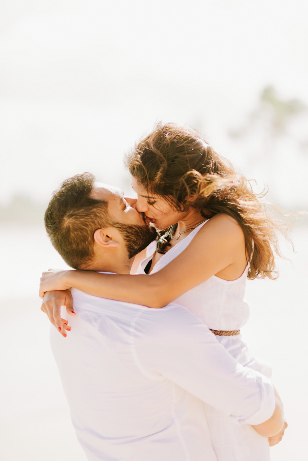 Приподняв на руки, жених целует невесту.