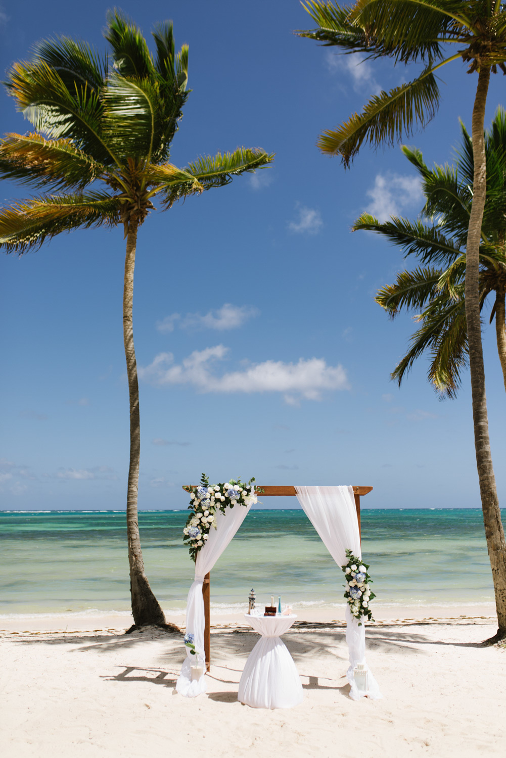 Wedding altar on the beach by the sea, decorated with white flowers and white curtains.