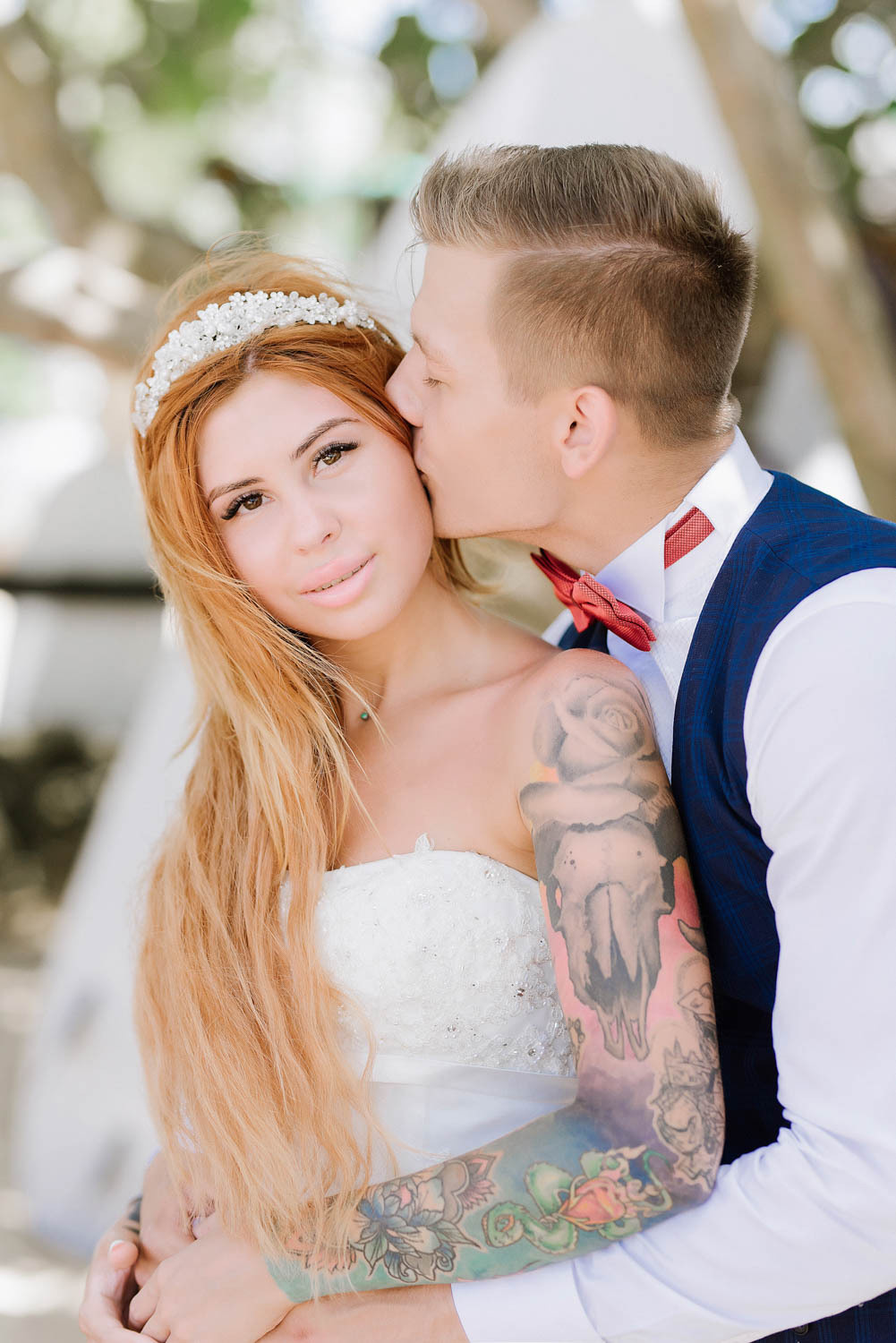 The groom kisses the bride on the cheek.