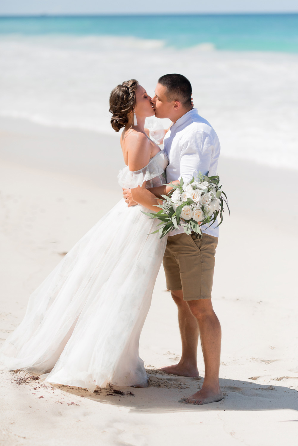 Жених с невестой целуются на фоне моря.