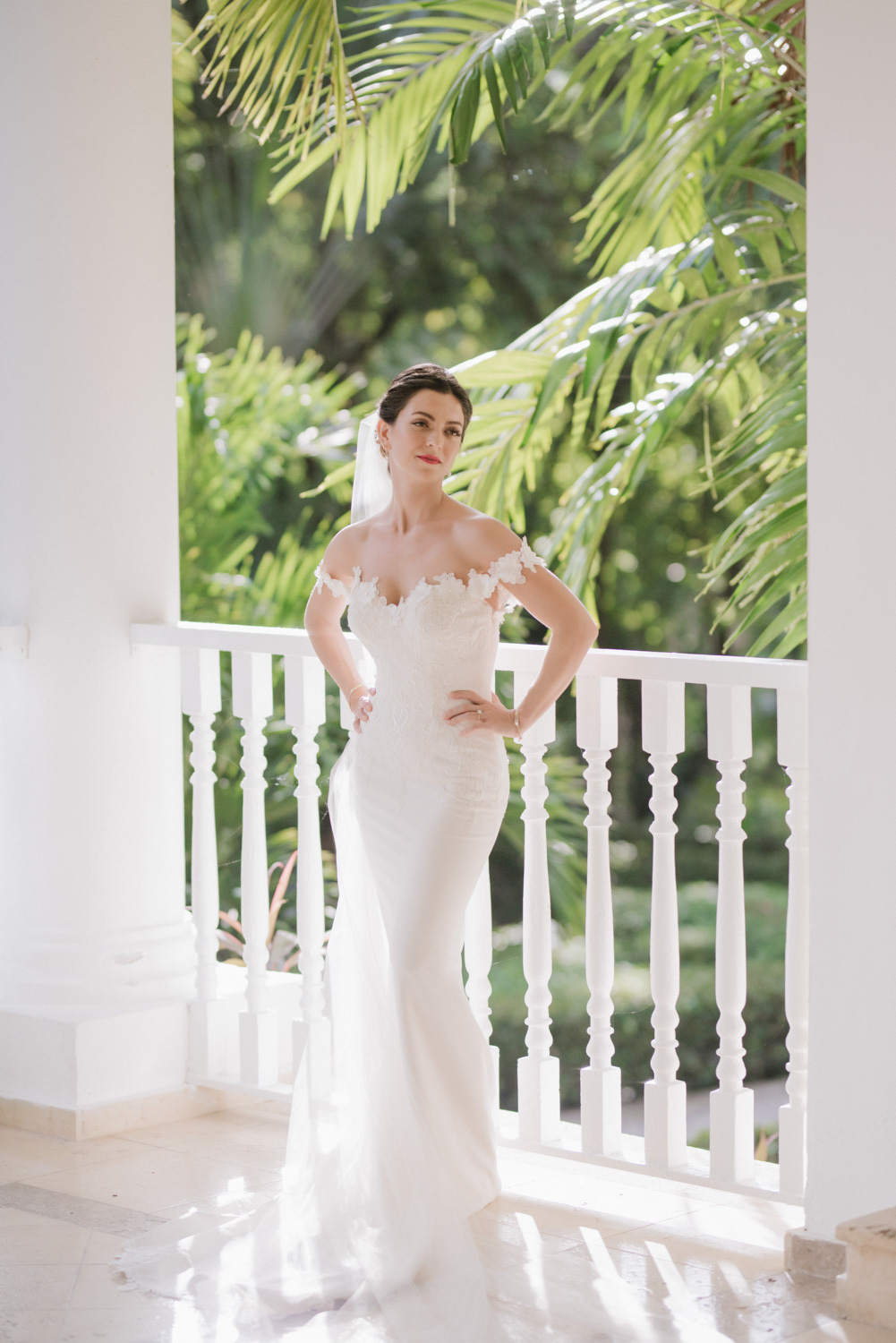 The bride stands at the pillar, posing for a photographer.