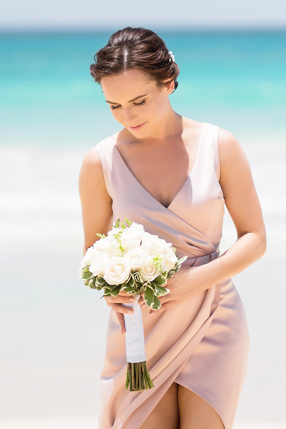 Невеста с букетом цветов на фоне белого песка и бирюзового моря.