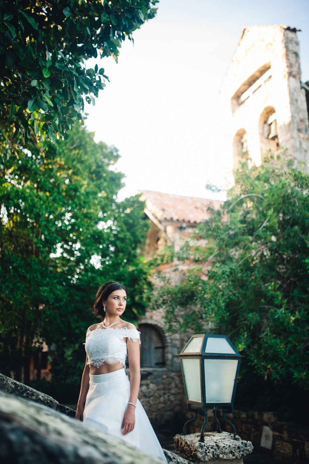 Bride at the tower lantern on the background of green trees.