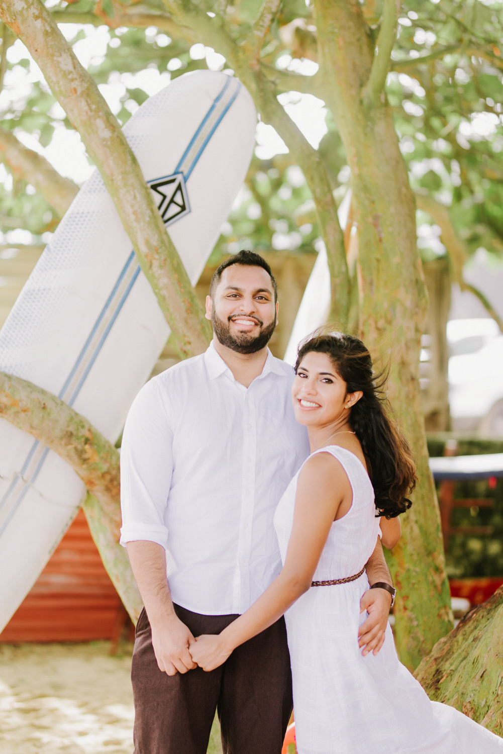 Жених с невестой стоят под деревом, взявшись за руки.