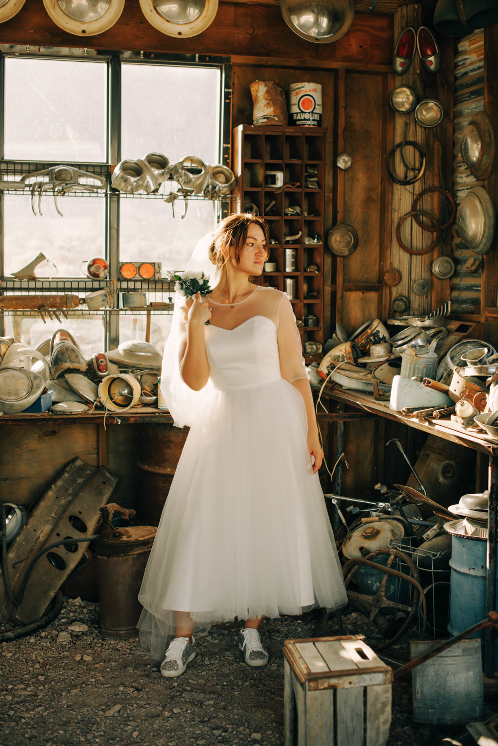 Невеста стоит среди заброшенного гаража.