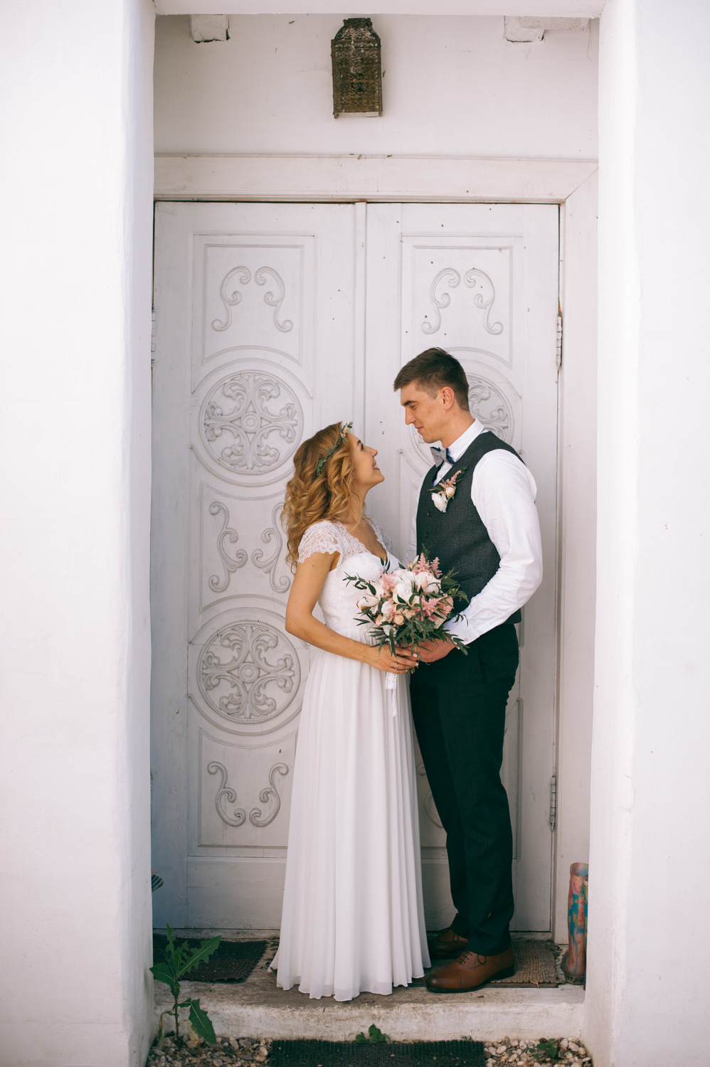 Bride and groom at the entrance to the white building.