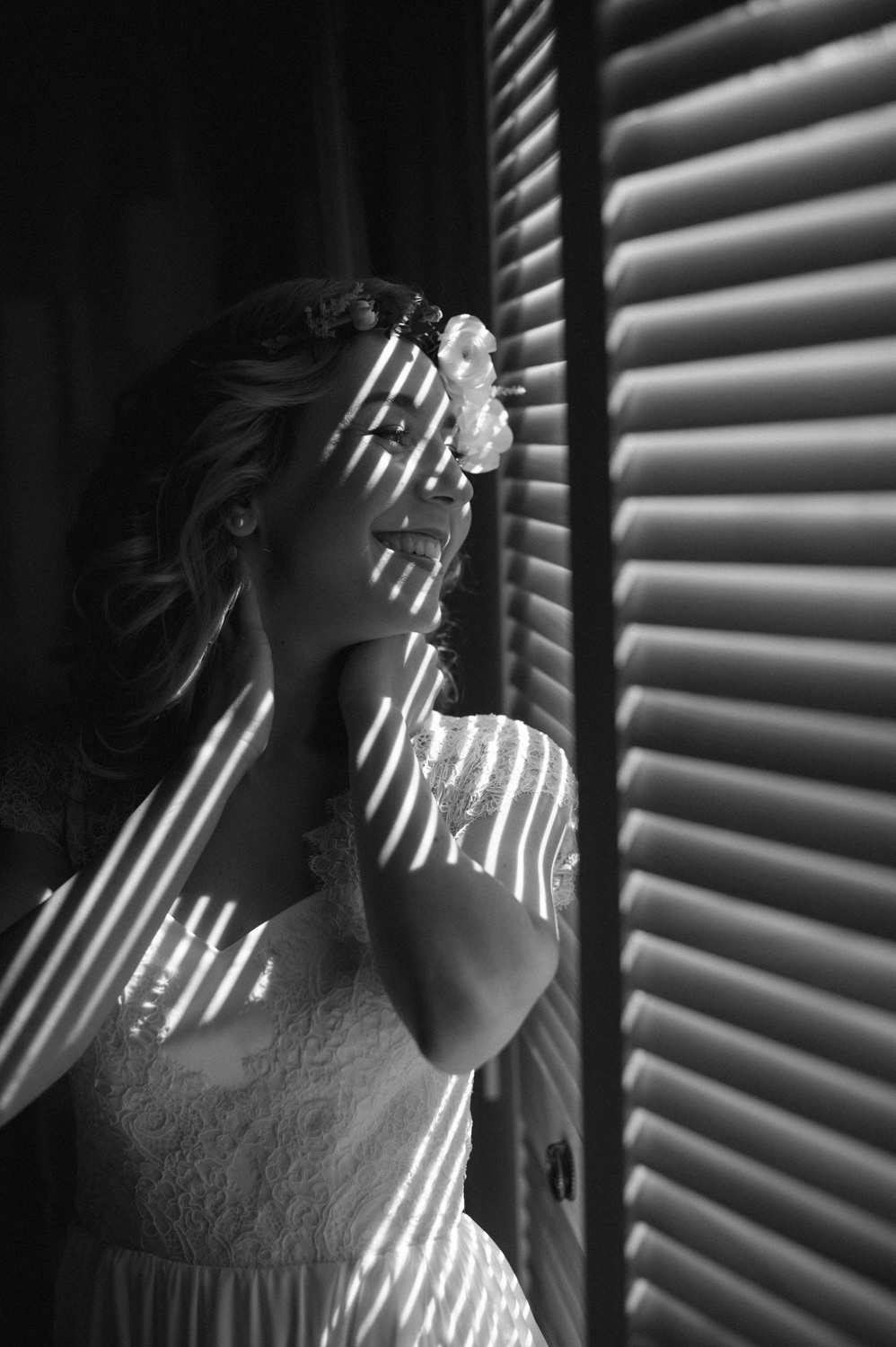 Bride's face in black and white stripes from the light coming through the blinds on a black and white background.