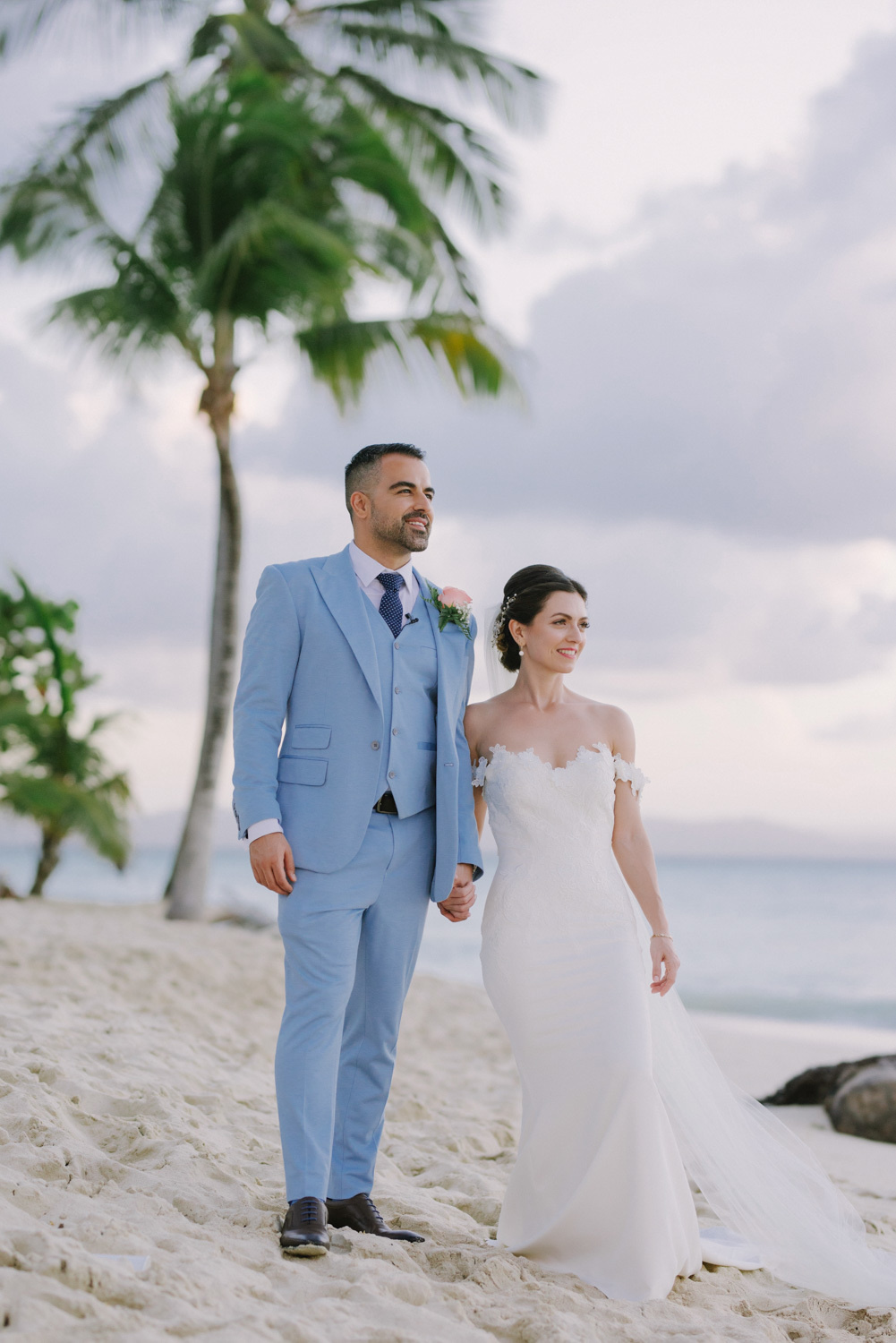 Bride and groom on the background of the sea, beach with palm trees look at the rising sun.