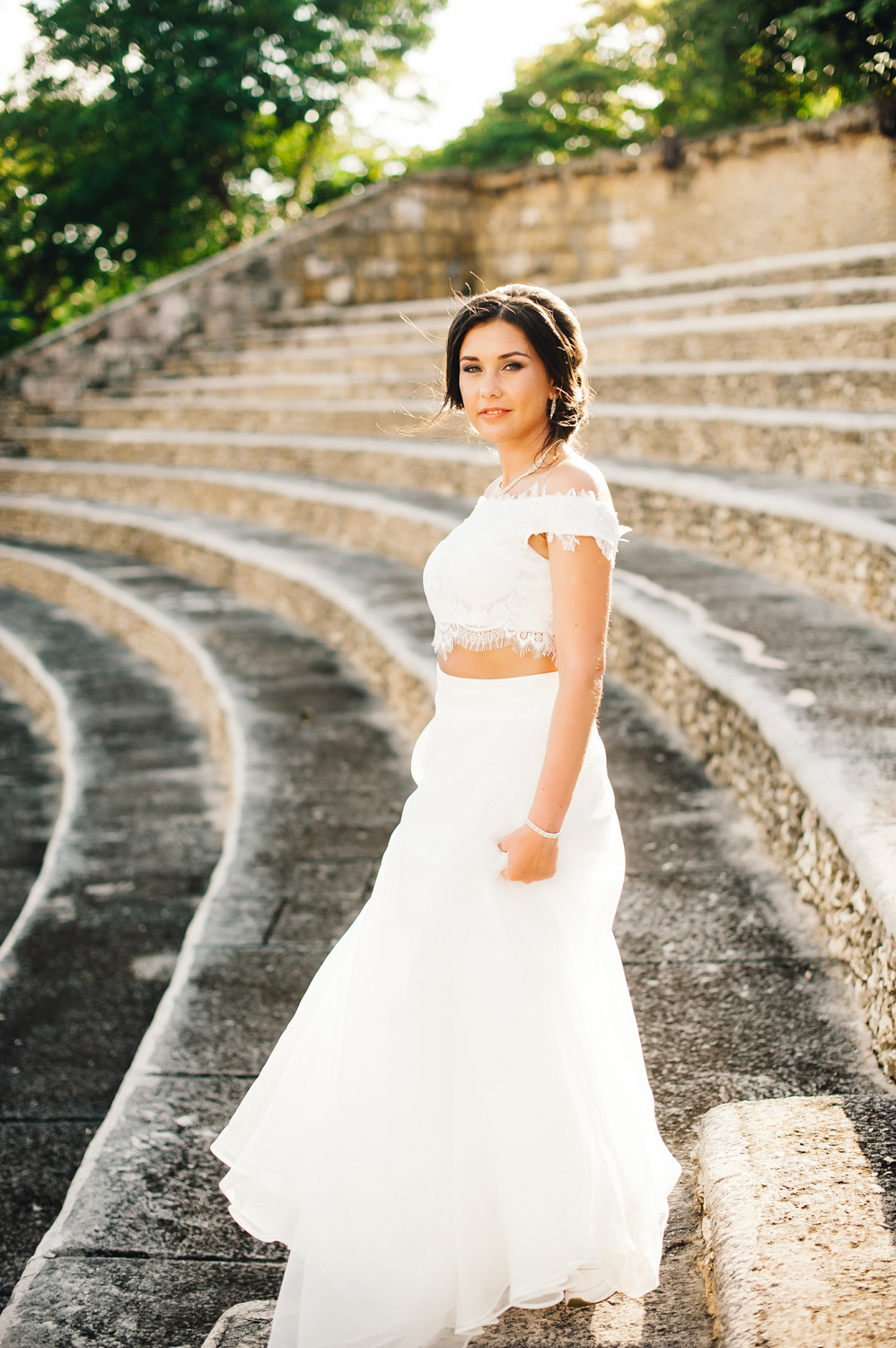 Bride in a long white dress on a stone staircase.
