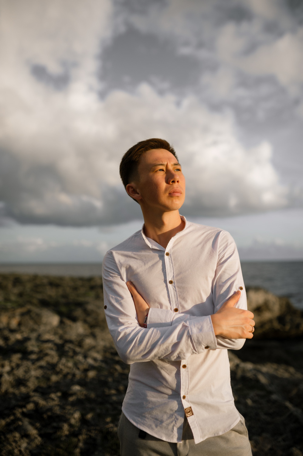 Жених смотрит в небо на фоне леса и моря.