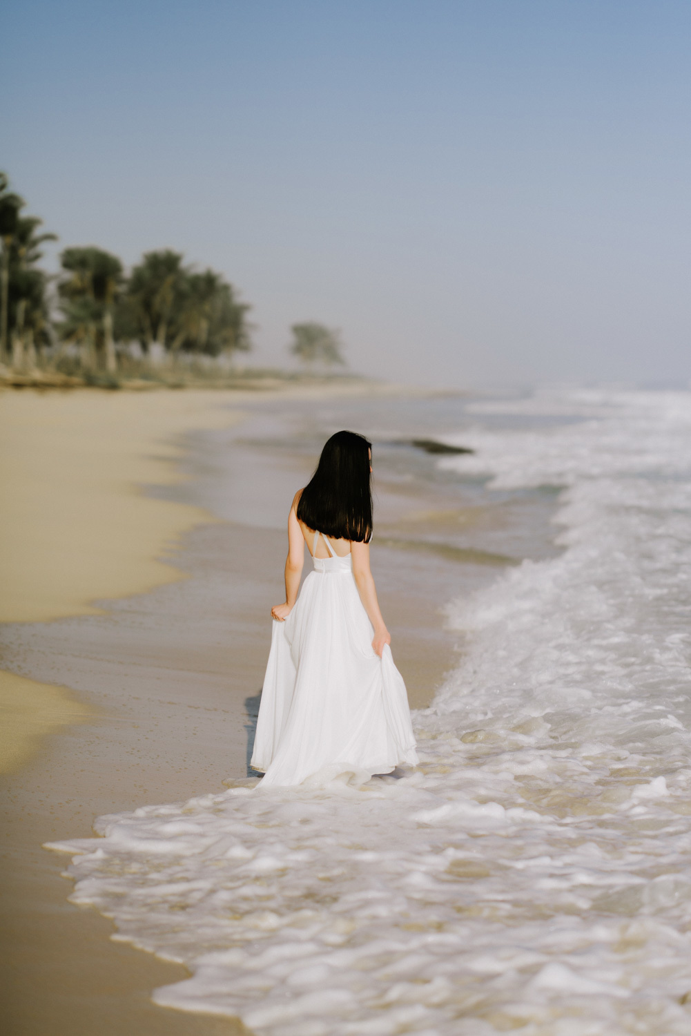 Bride on the beach with palm trees by the sea water.