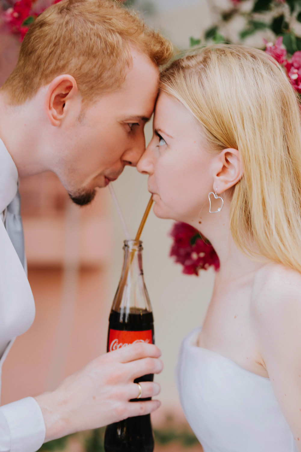 Жених и невеста смотрят друг другу в глаза. Жених держит бутылку с напитком.