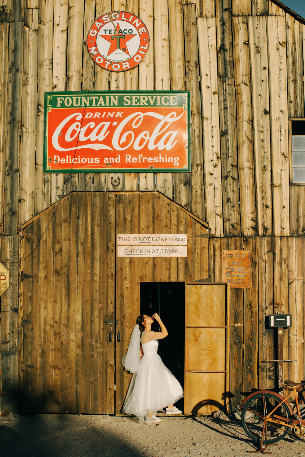 Невеста у входа в старое деревянное здание с вывеской COCA-COLA.