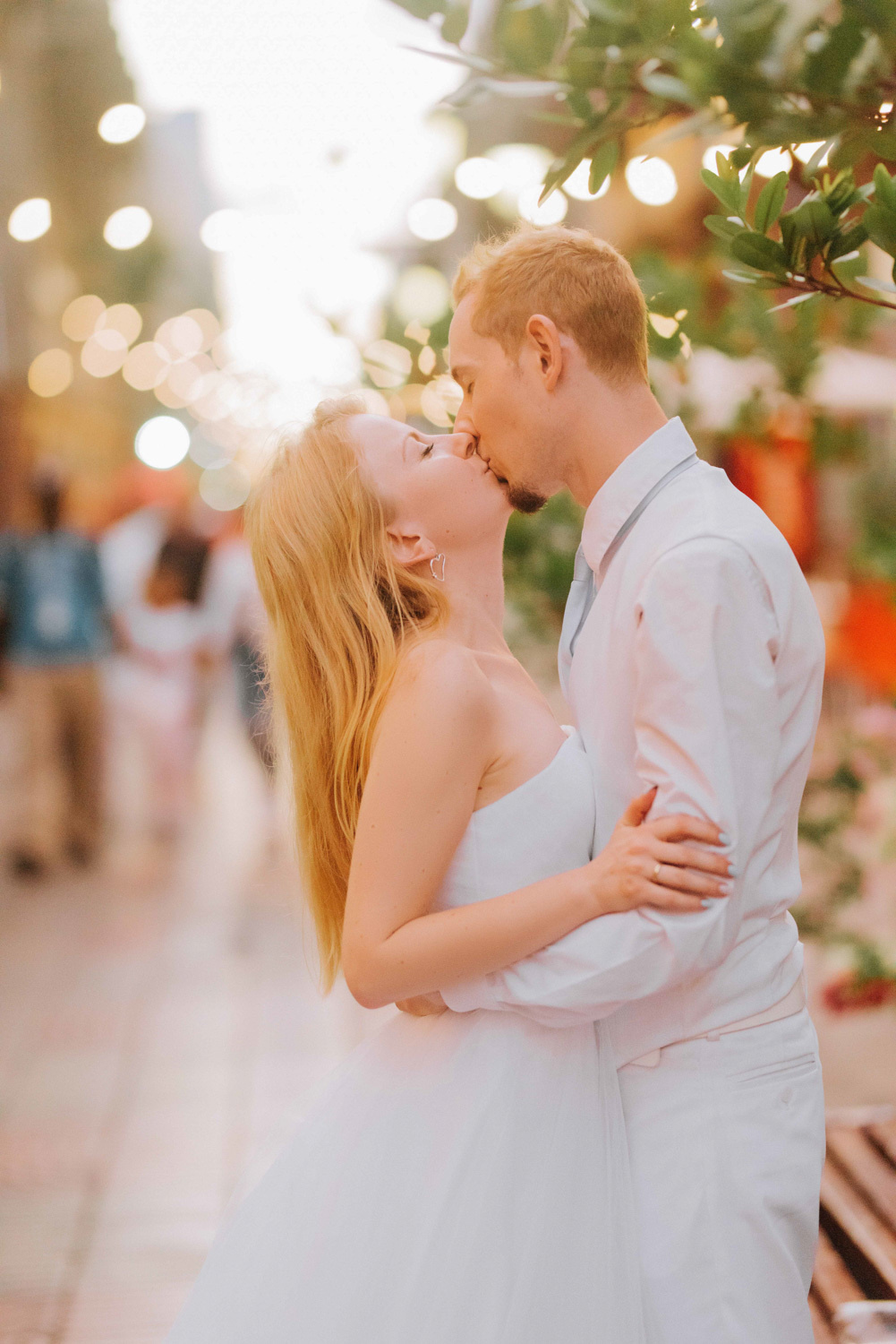 Молодожены целуются на фоне вечерней улицы.