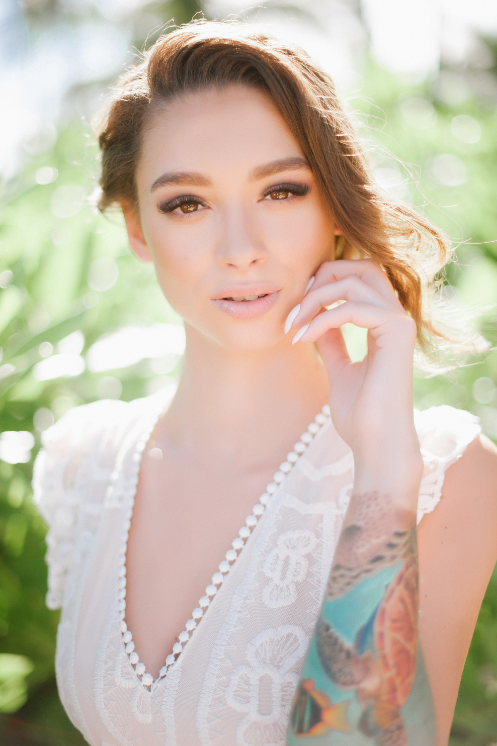 The bride holds her hand to her face, with a colored tattoo on her arm.